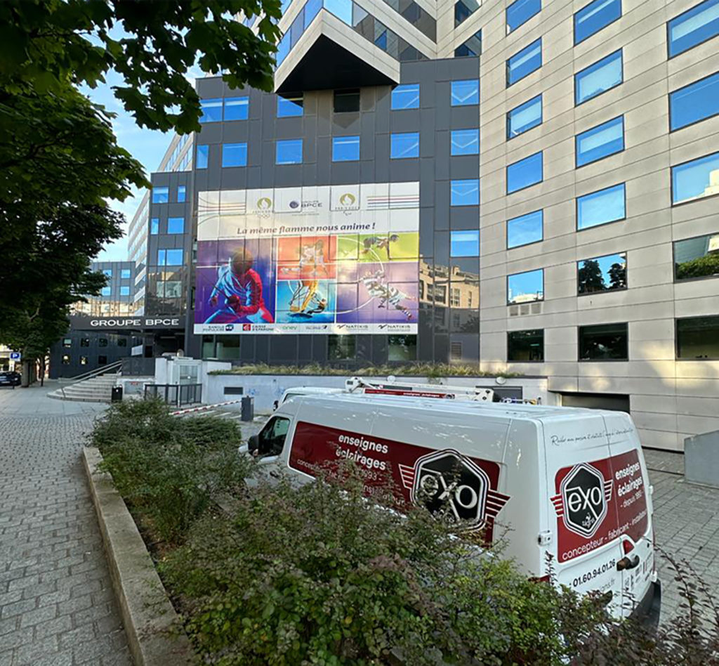 Les véhicules Exo Signs devant une façade fraîchement couverte de grandes impressions sur adhésif micro-perforé